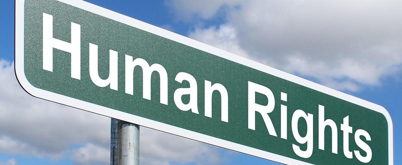 Schild mit der Aufschrift „Human Rights“ vor blauem Himmel. Das Bild steht im Kontext der internationalen Debatte über menschenrechtliche Sorgfaltspflichten von Unternehmen und den Schutz von Menschenrechten in globalen Lieferketten.