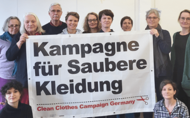 Menschen stehen gemeinsam um das Logo der Kampagne für Saubere Kleidung und symbolisieren den Einsatz für ein gerechtes Textilgesetz und menschenwürdige Arbeitsbedingungen entlang globaler Lieferketten.